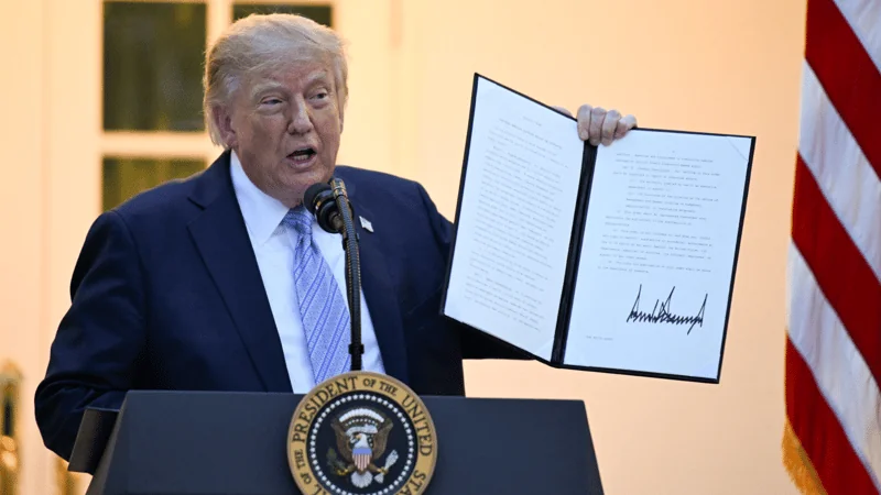 Трамп тримає відкриту папку з підписаним документом біля президентської трибуни