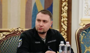 Кирило Буданов у чорній куртці сидить за столом на офіційній зустрічі