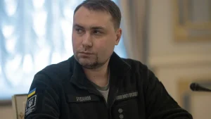 Кирило Буданов у чорній куртці з шевроном сидить за столом у кабінеті