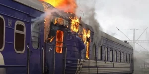 Палаючий синій пасажирський вагон українського поїзда на залізничній станції