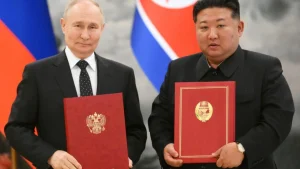 Путін і Кім Чен Ин тримають червоні папки з гербами на тлі прапорів