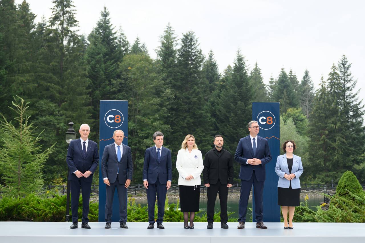 Лідери країн на саміті C8 біля синіх стендів серед карпатського лісу