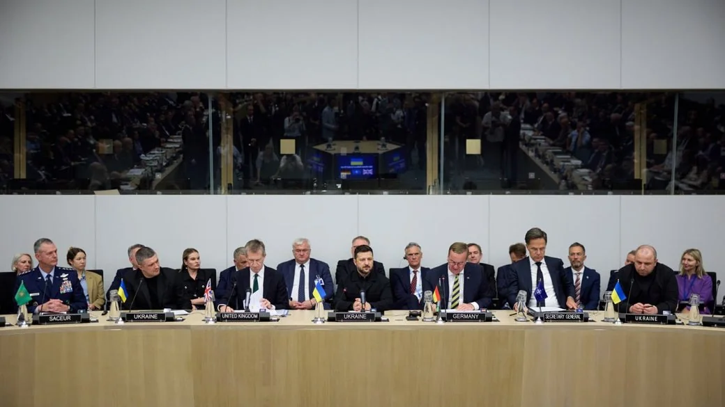 Учасники засідання за столом із табличками країн і прапорами України